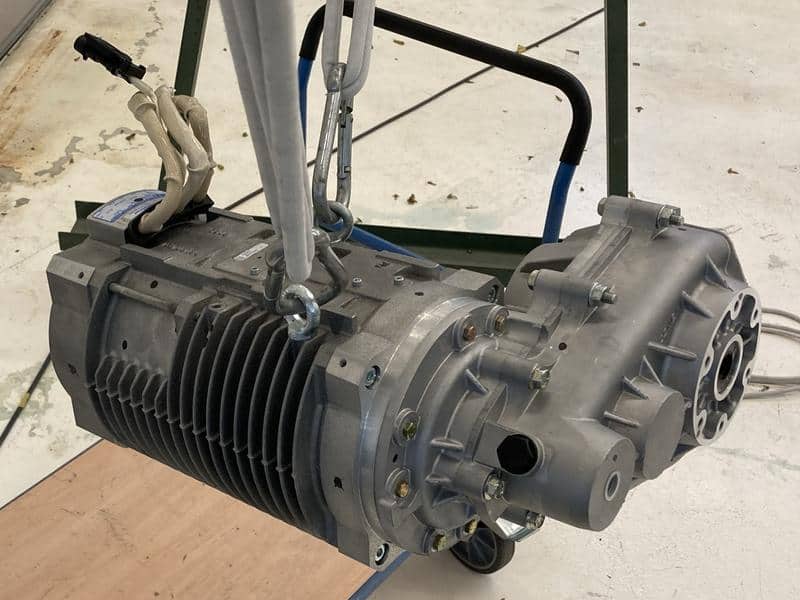 The real e-motor and gearbox hanging from a hoist in a workshop, ready for a modal test